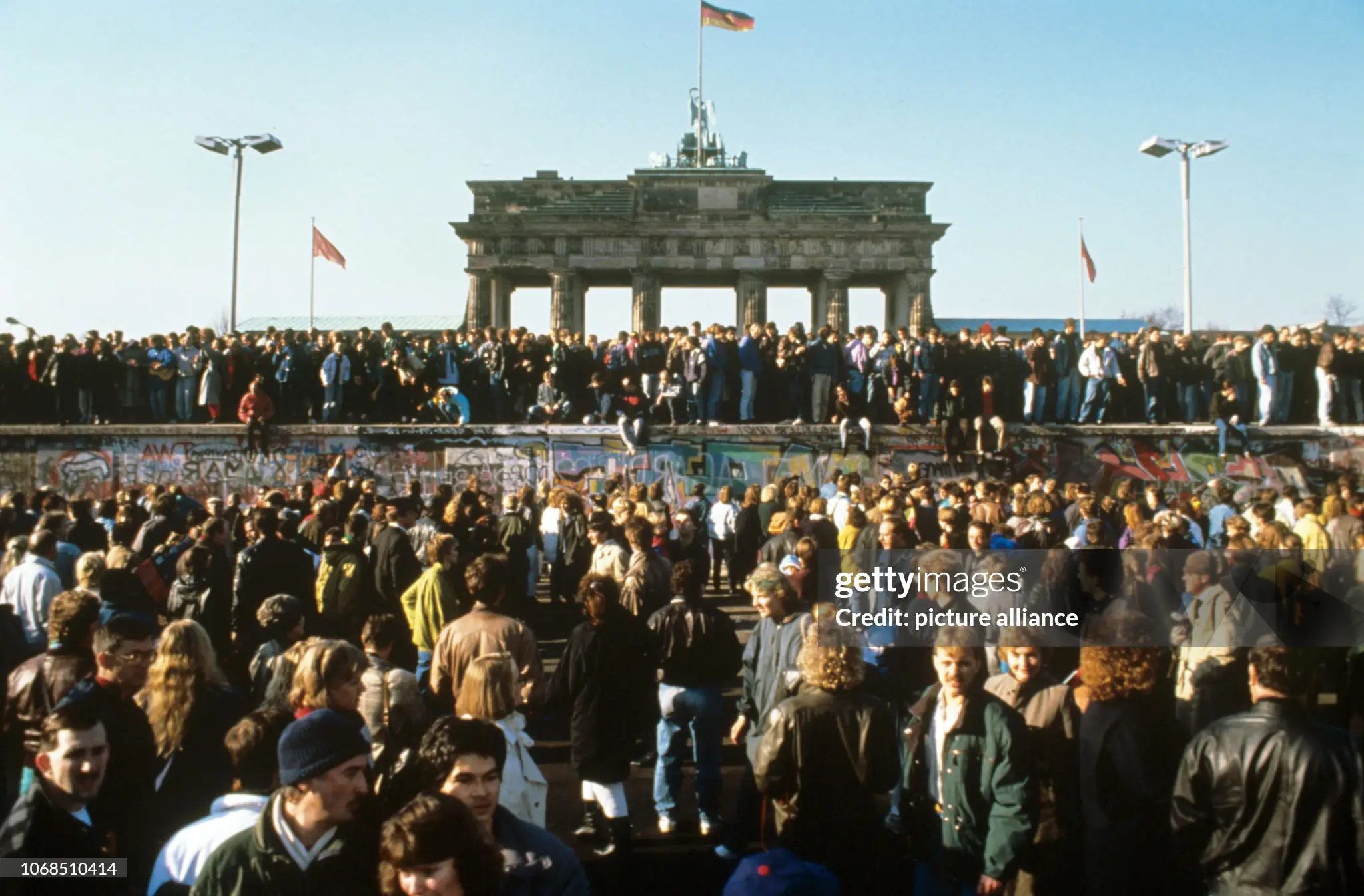 People at the west side of the Berlin Wall at Potsdamer Platz in November 1989, with the wall already chipped and covered in graffiti.